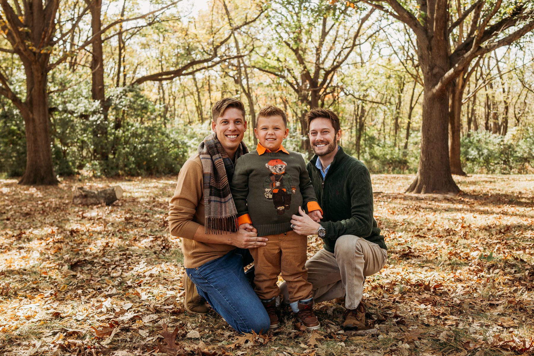 Shane, Tyler, and Carter kneeling together in a park in autumn